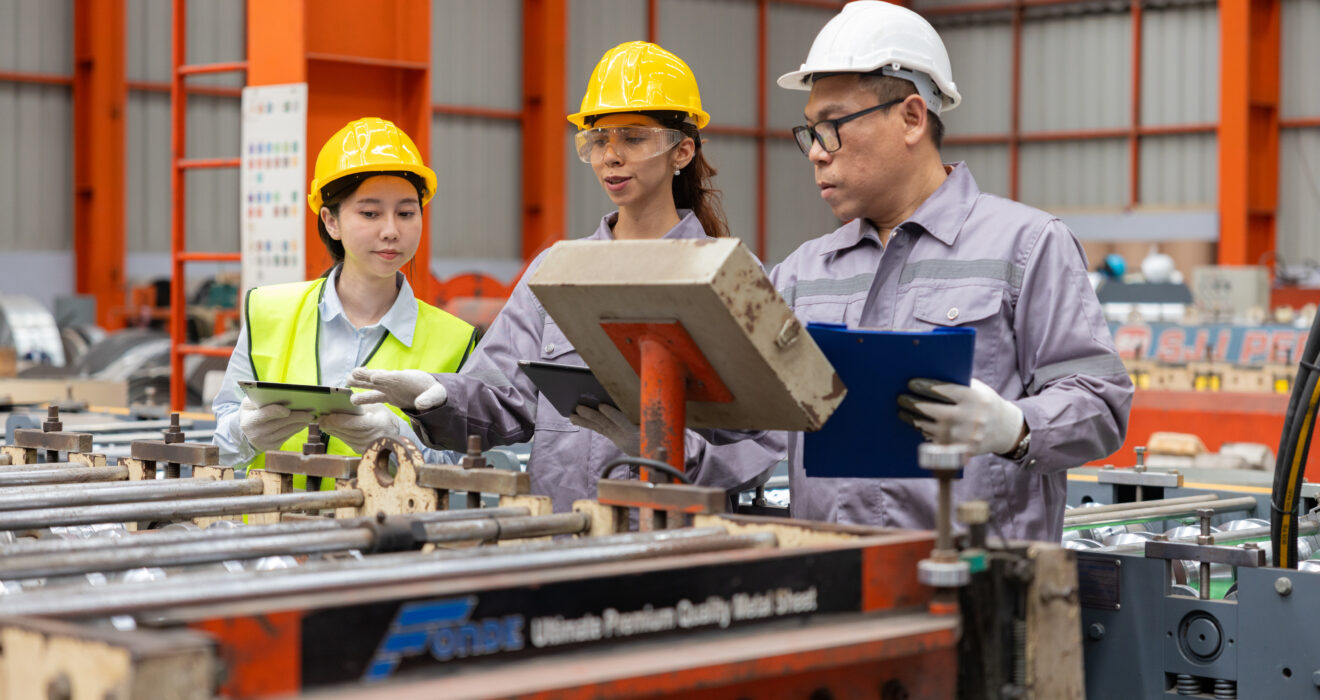 Engineers discussing machinery in manufacturing plant