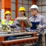 Engineers discussing machinery in manufacturing plant